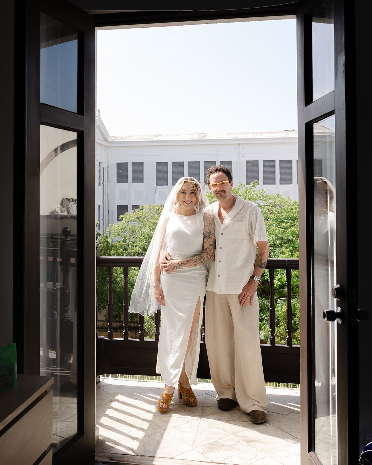 bride and groom showcasing how to smile naturally in wedding photos with a posed picture of them on the balcony