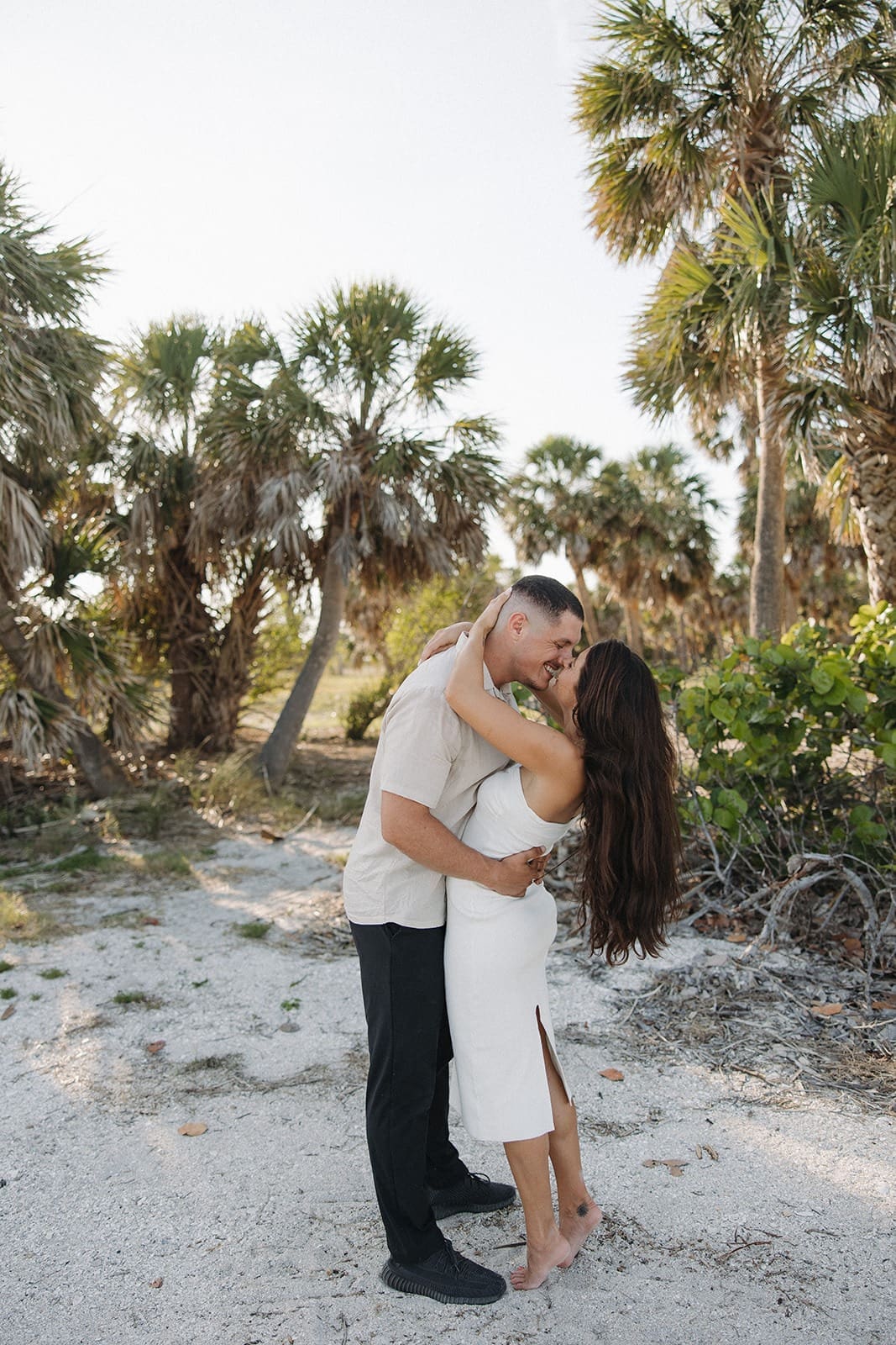 bride and groom kissing on the beach during their portrait session