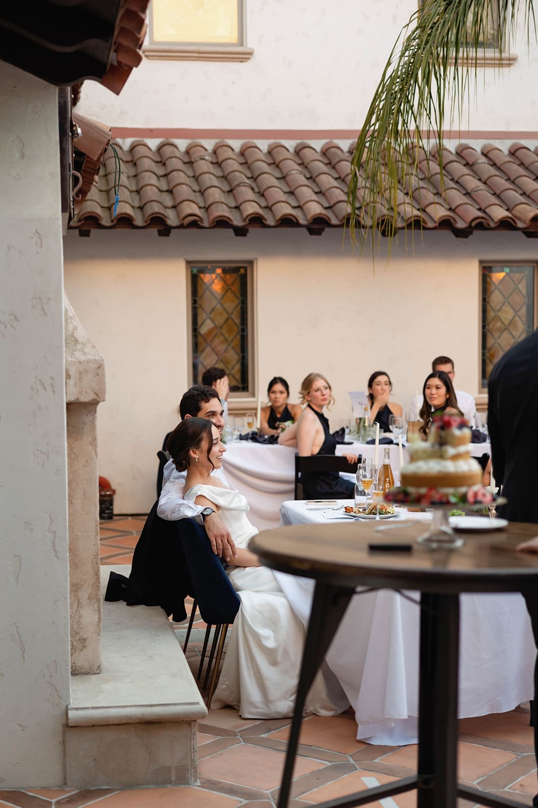 authentic photo of a bride and groom sitting at their wedding reception table 