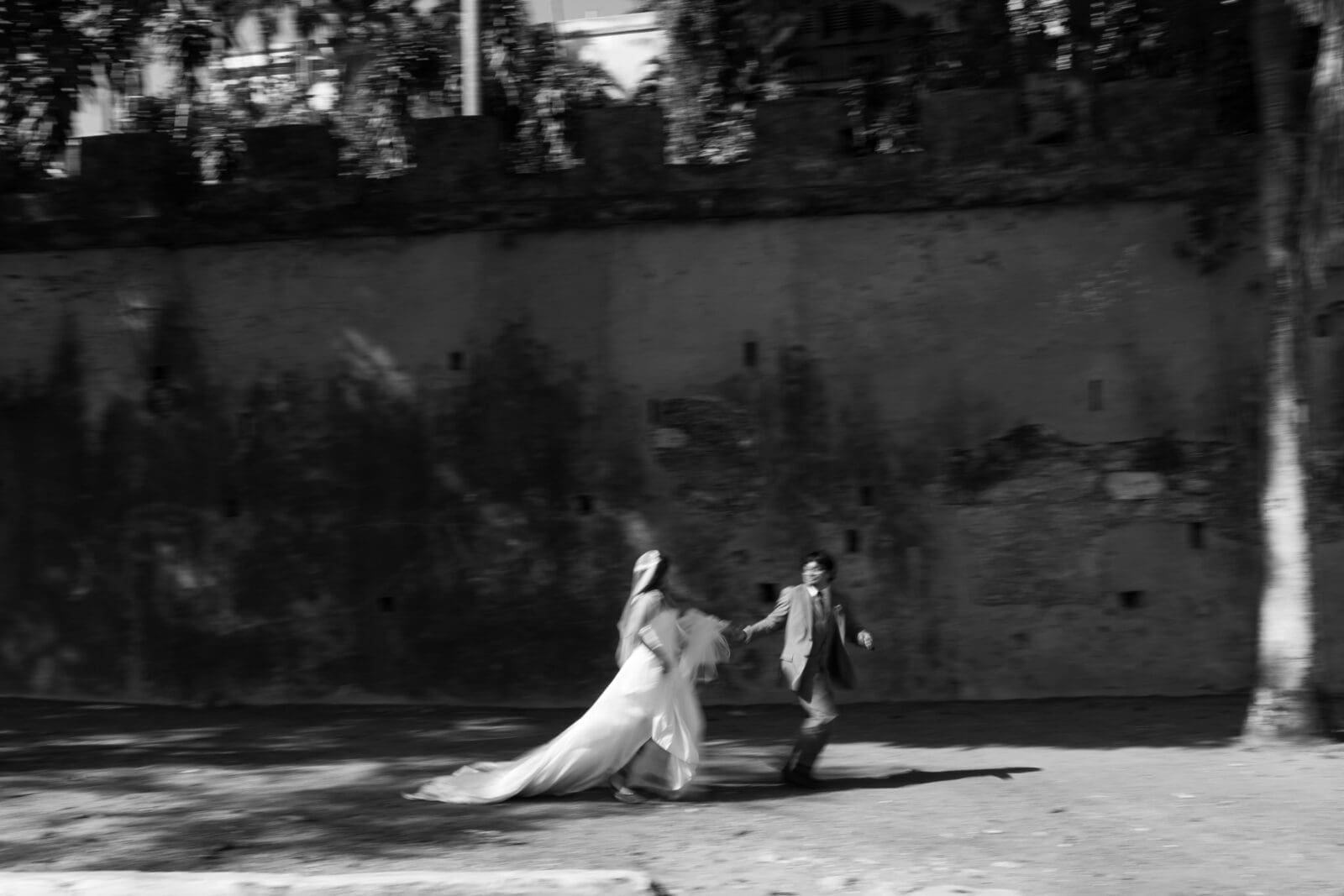 Bride and groom walking together beside a historic wall in Old San Juan, Puerto Rico