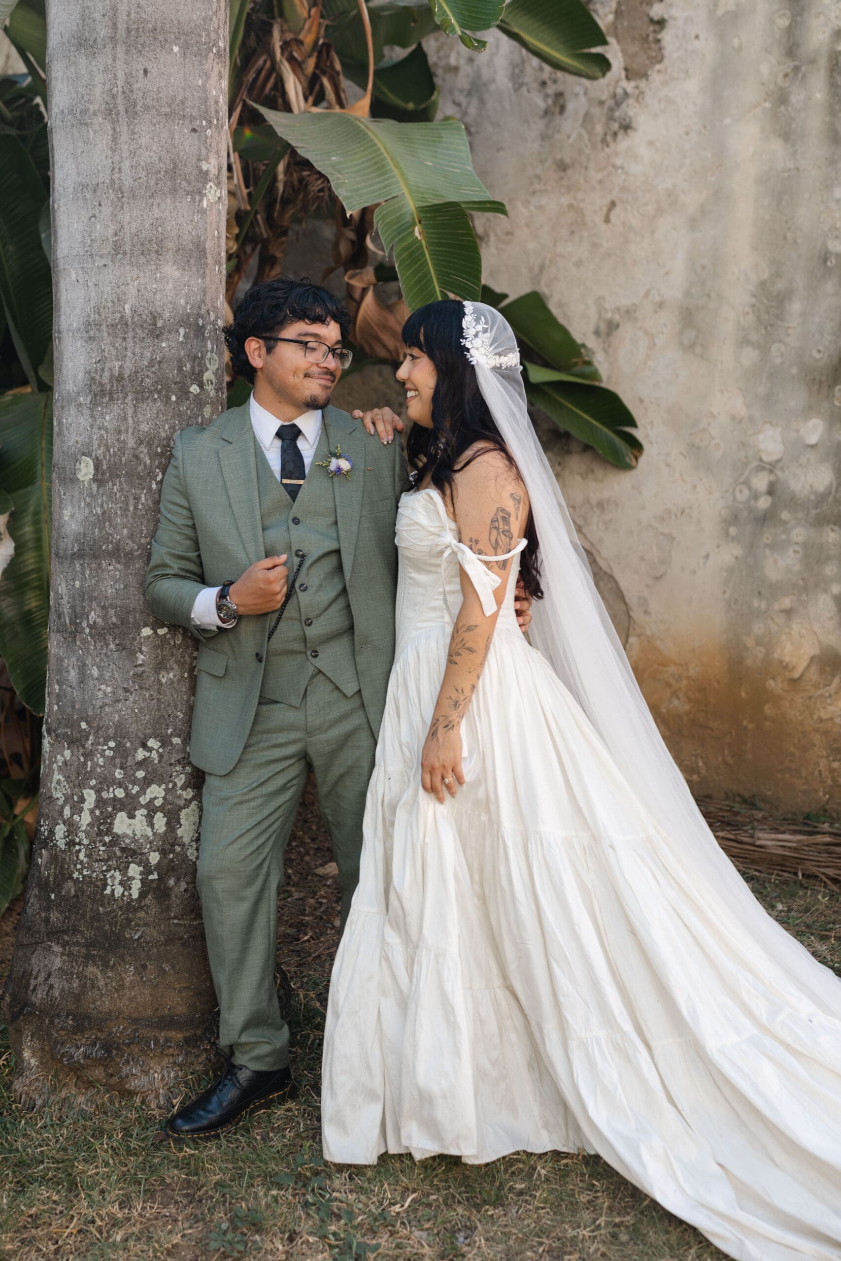 Newlyweds posing together beside a palm tree during their San Juan wedding