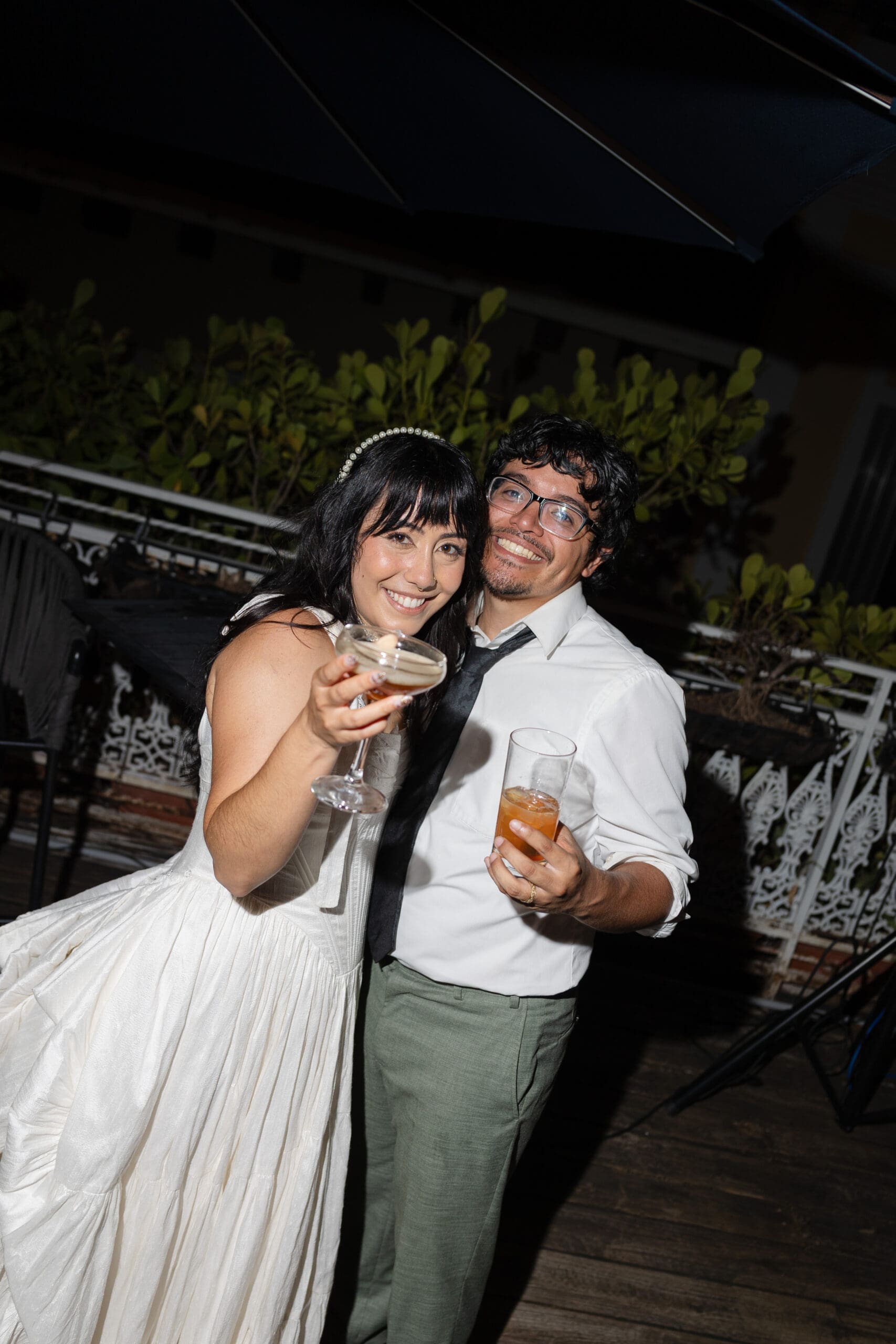 Newlyweds smiling together with drinks during their outdoor wedding reception