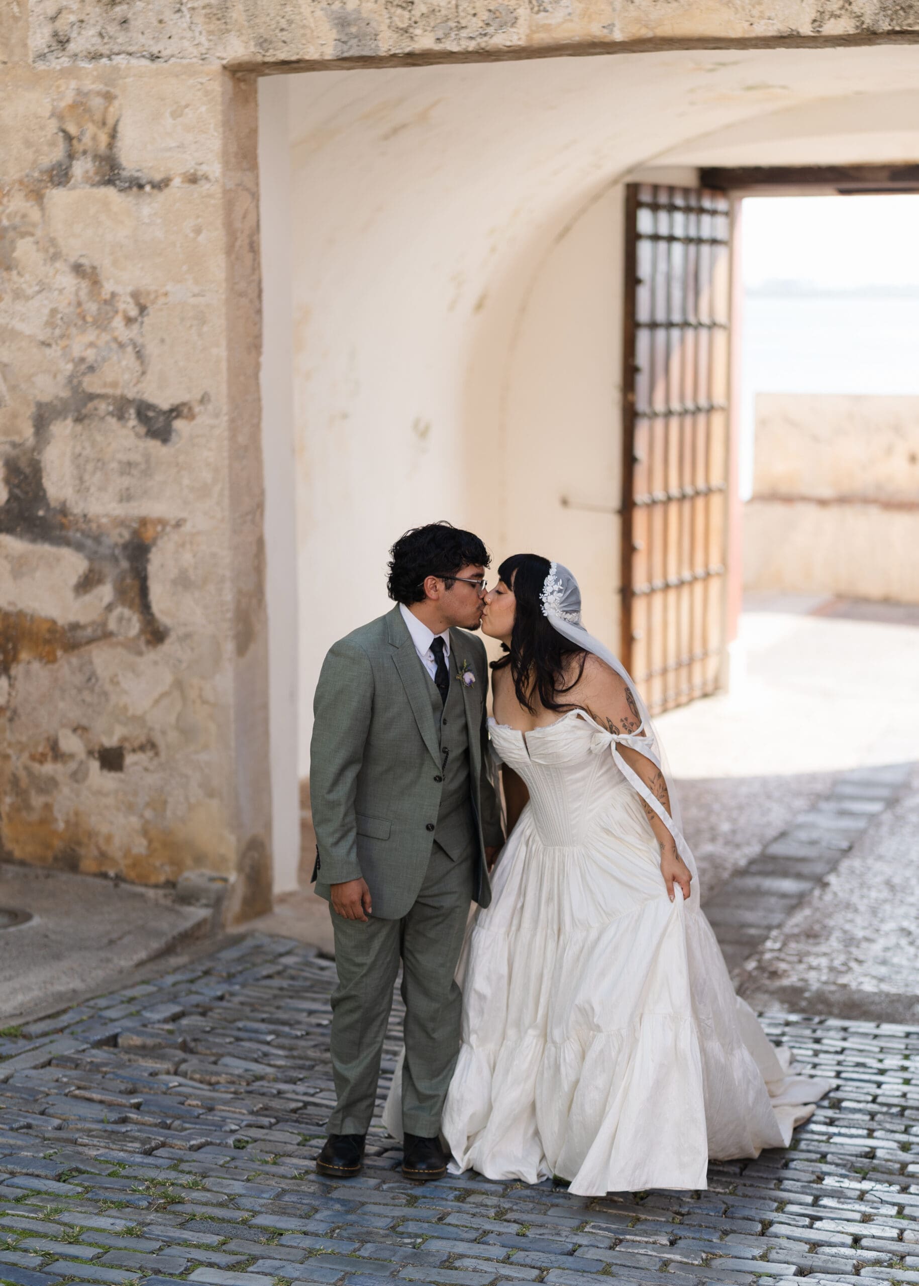 Newlyweds kissing beneath a stone archway in Old San Juan, Puerto Rico