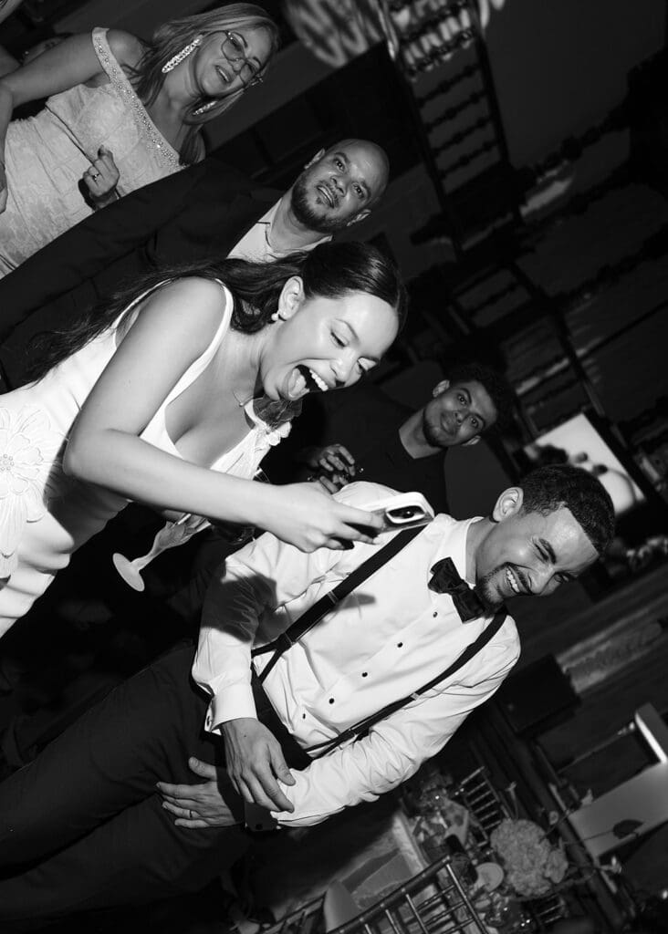 Black-and-white photo of the bride and groom laughing together on the wedding dance floor.
