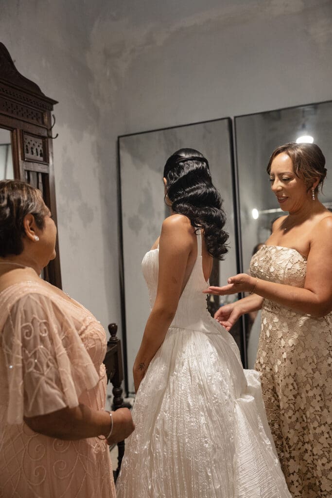 Bride getting ready with family members helping her into her wedding dress.