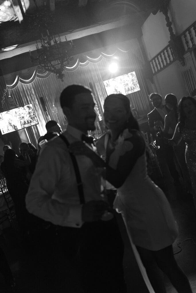 Black-and-white photo of the bride and groom dancing together during their wedding reception