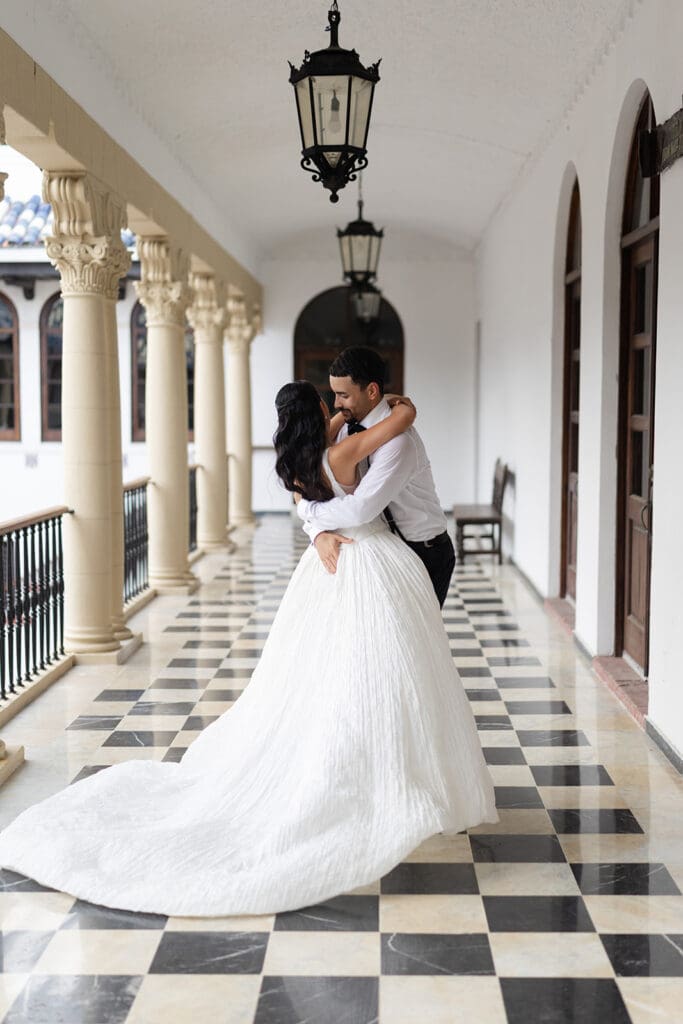 Bride and groom embrace in the checkerboard-tiled corridor at Casa de España in Puerto Rico.