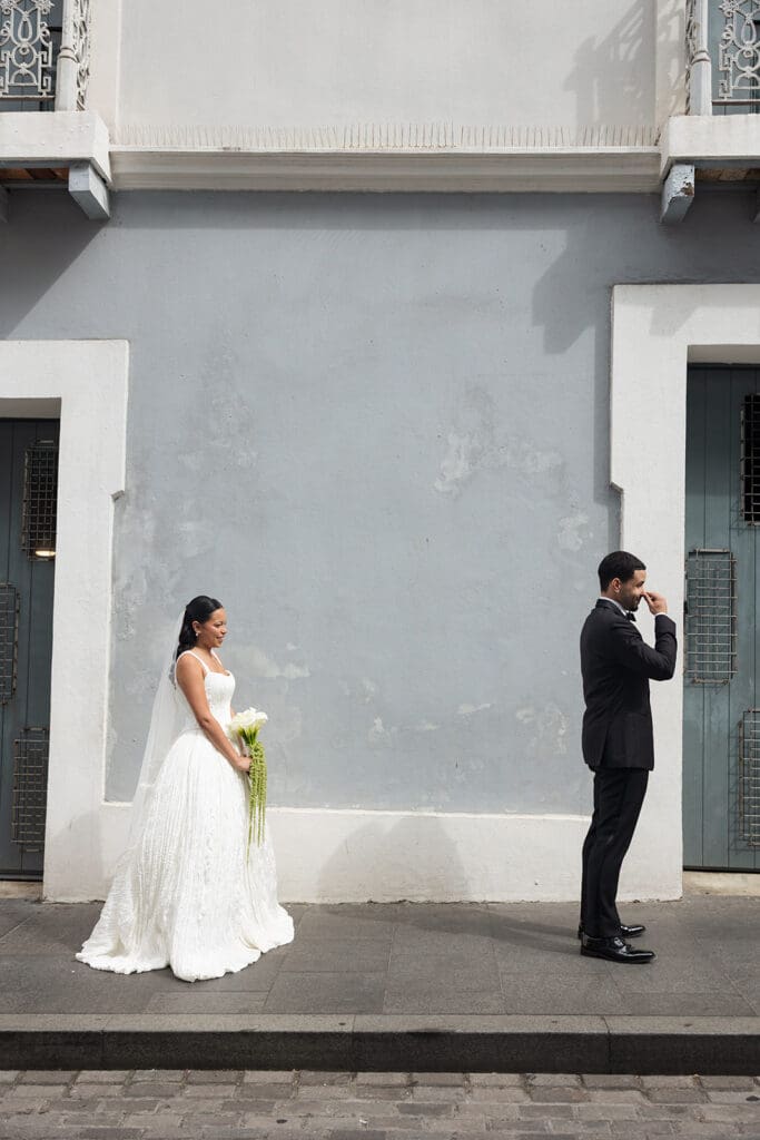 Bride approaches the groom from behind during their first look on a street in Old San Juan.
