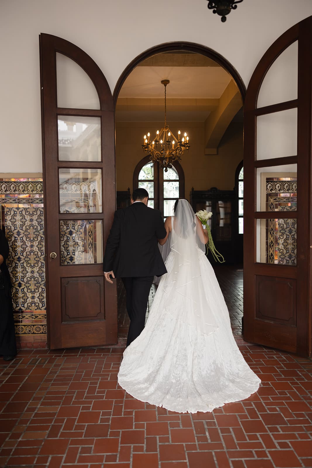 Bride and groom walk through an arched doorway at Casa de España after their wedding ceremony.