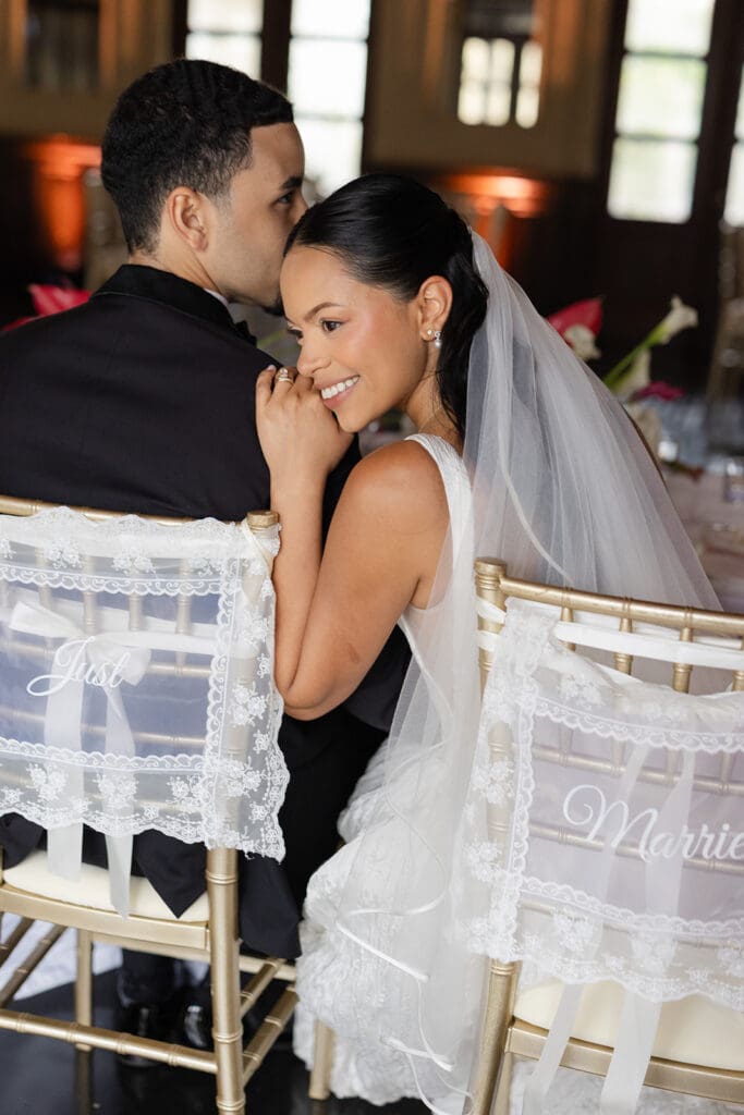 Bride smiles over her shoulder while seated beside the groom at their Casa de España wedding reception.