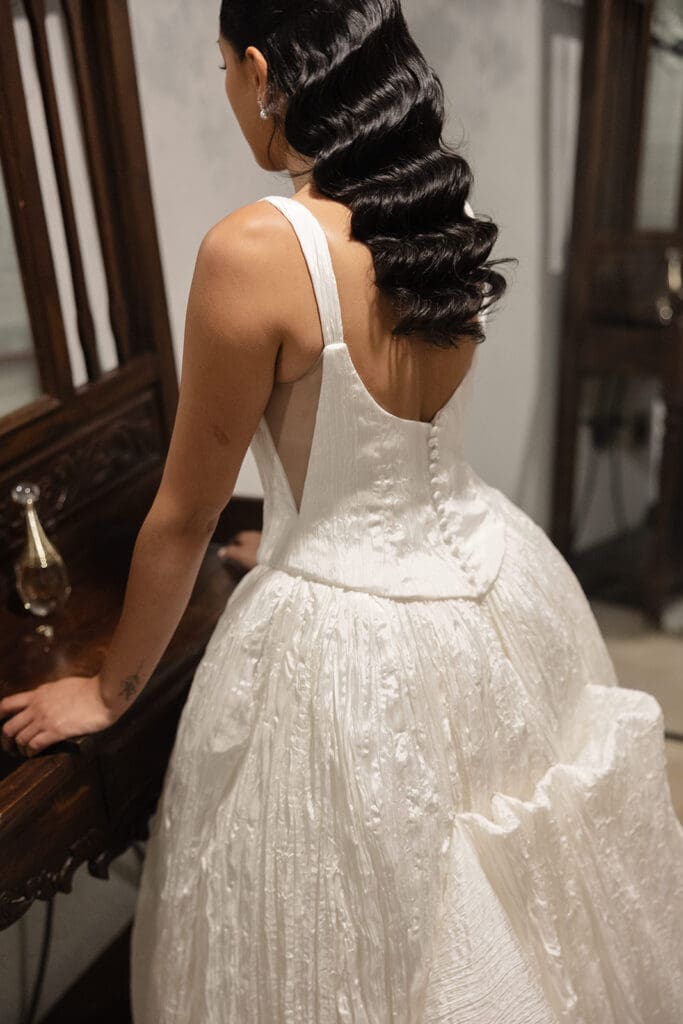 Close-up of the bride’s half-up hairstyle and textured wedding dress while getting ready.