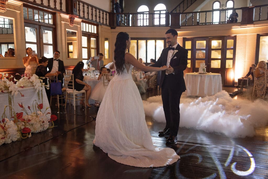 Bride and groom holding hands during their first dance in the Casa de España ballroom.