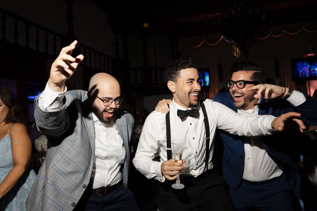 Groom laughing and dancing with wedding guests during the reception celebration.