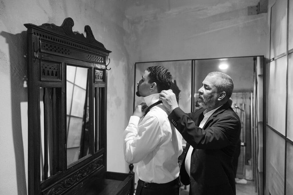 Groom getting ready with his father helping adjust his collar before the wedding.