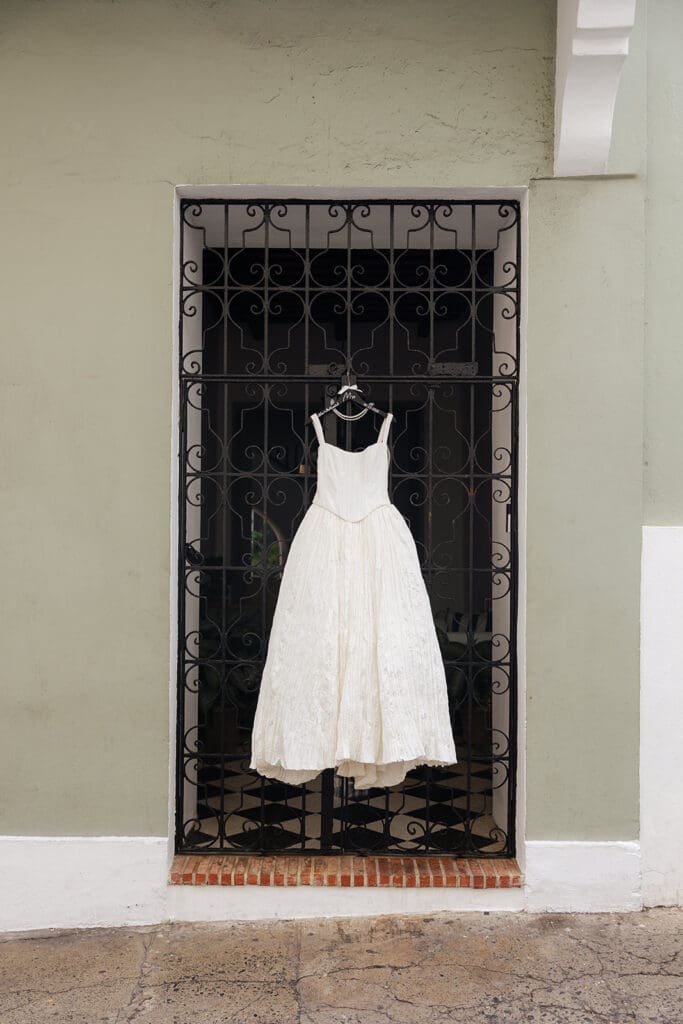 Jenny Yoo wedding dress hanging from a wrought-iron gate in Viejo San Juan.
