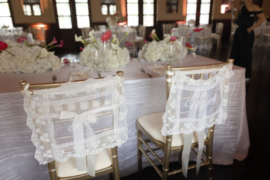Gold reception chairs decorated with lace “Just” and “Married” signs at a Casa de España wedding.