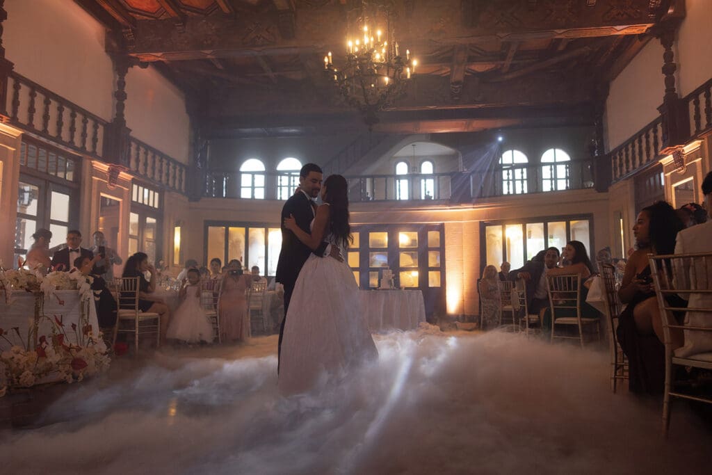 Bride and groom sharing their first dance on a low-fog dance floor inside the historic ballroom.