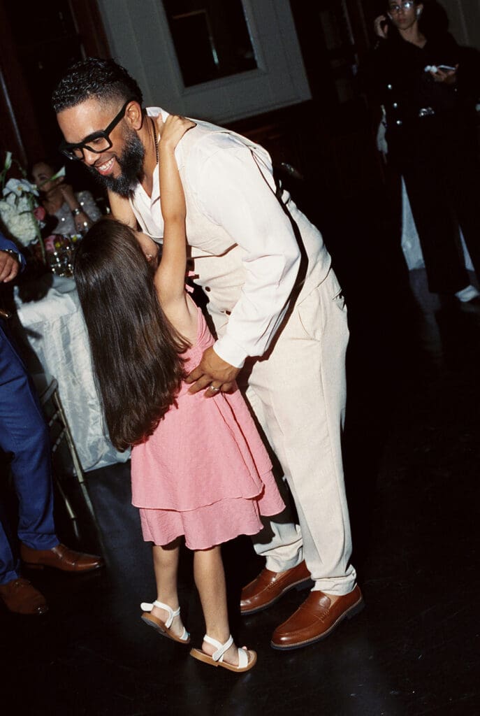 Young wedding guest hugging a family member during the reception celebration.