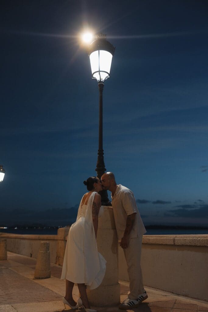 Couple kissing beneath a glowing streetlamp beside the waterfront during their Puerto Rico elopement.