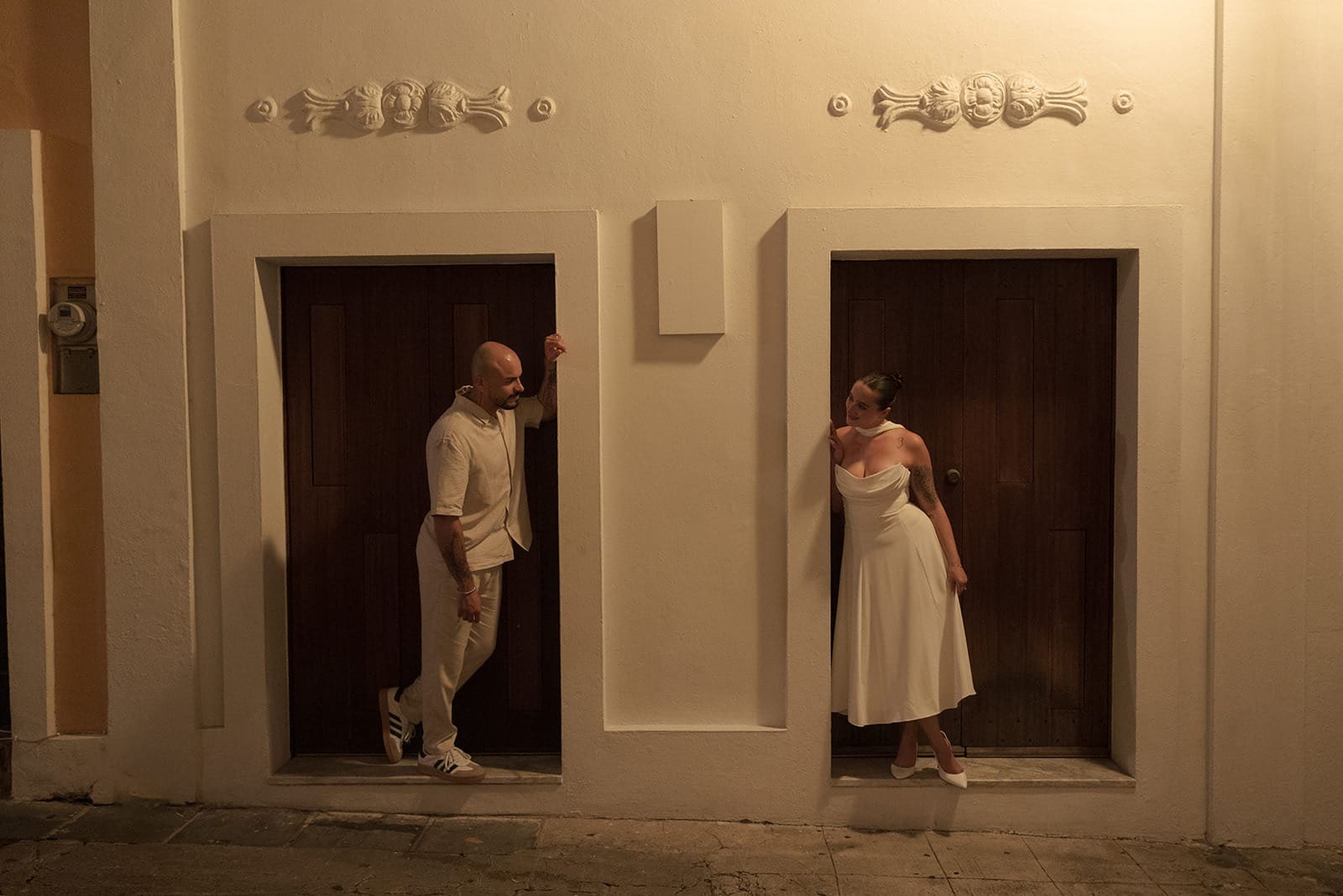 Bride and groom posing in separate recessed doorways of a historic building during their Puerto Rico elopement portraits in Old San Juan.