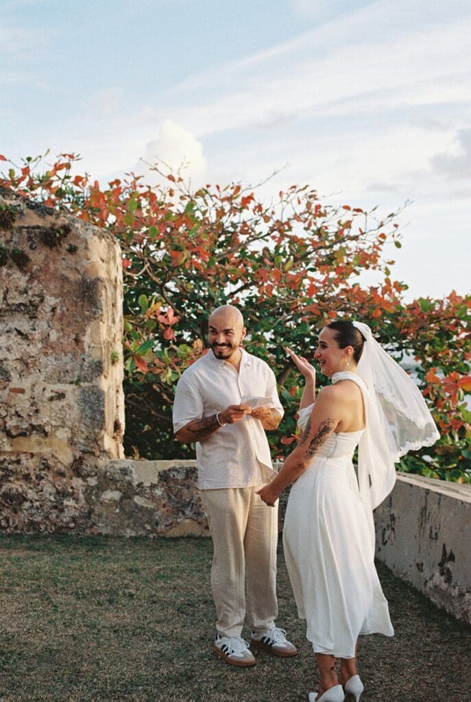 Couple holding hands and sharing a joyful moment while exchanging vows at their Old San Juan elopement.