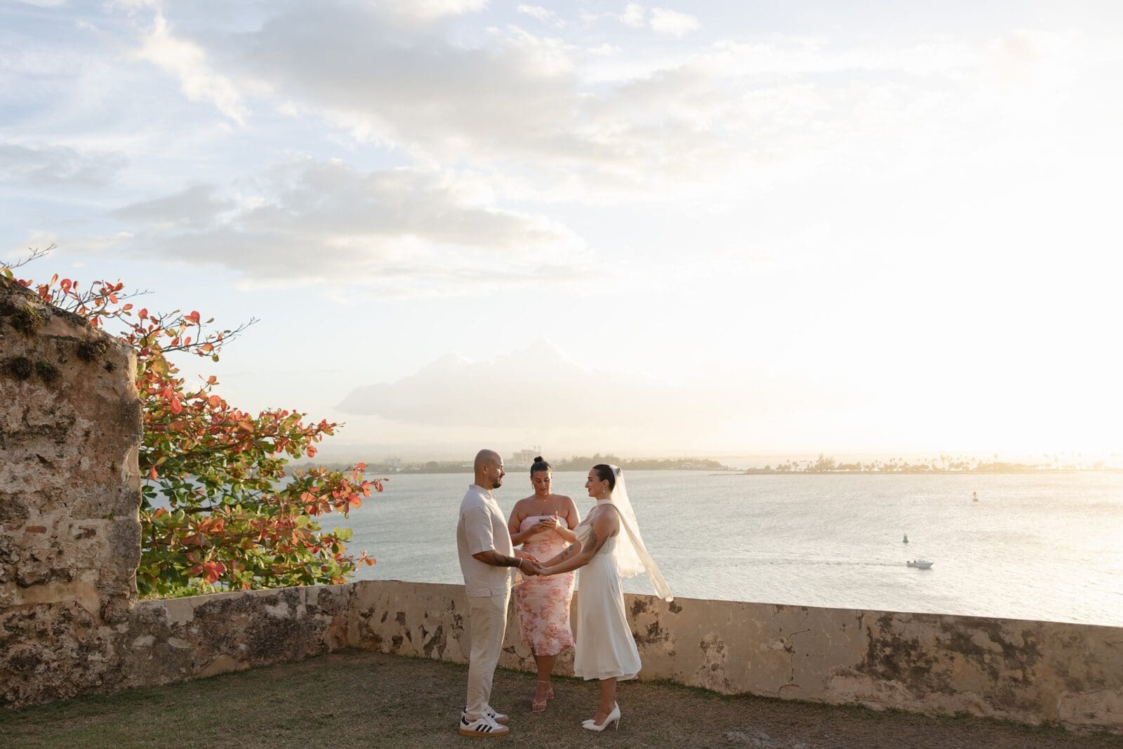 Couple exchanging vows during their intimate Puerto Rico elopement, with an officiant and ocean views in the background.