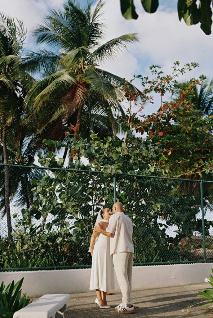 Couple sharing a kiss beneath palm trees during their intimate Puerto Rico elopement.