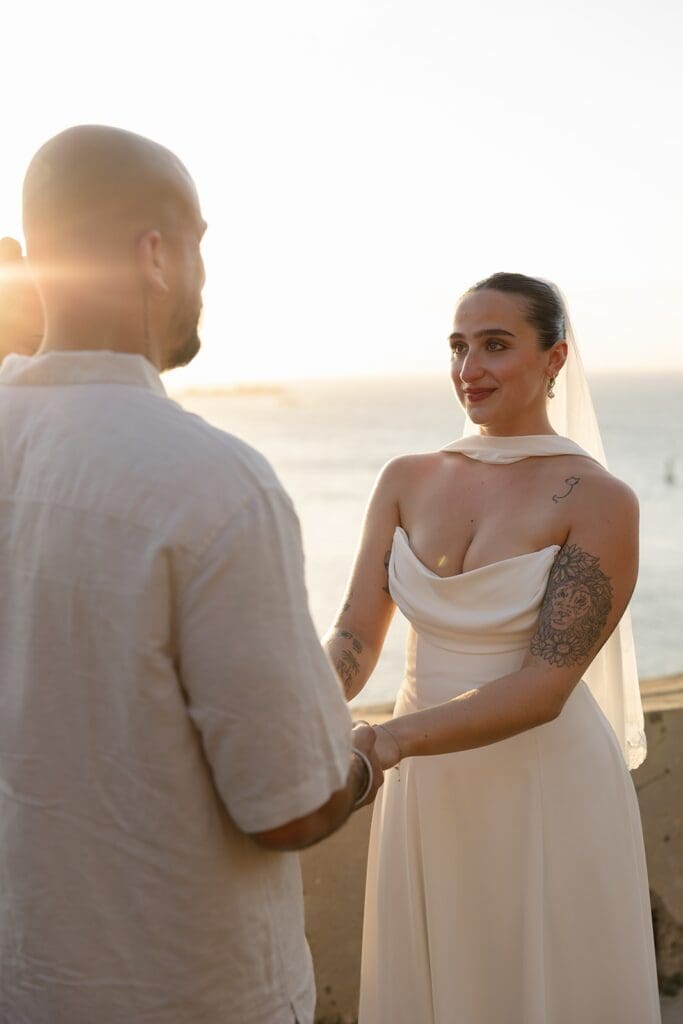 Bride smiling at her partner while holding hands during their intimate Puerto Rico elopement ceremony at sunset.